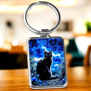 Porte-clés rectangulaire avec un chat noir sur un fond bleu nuit.