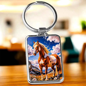 Porte-clés carré en métal avec une image de cheval marron et blanc sur fond de ciel nuageux.
