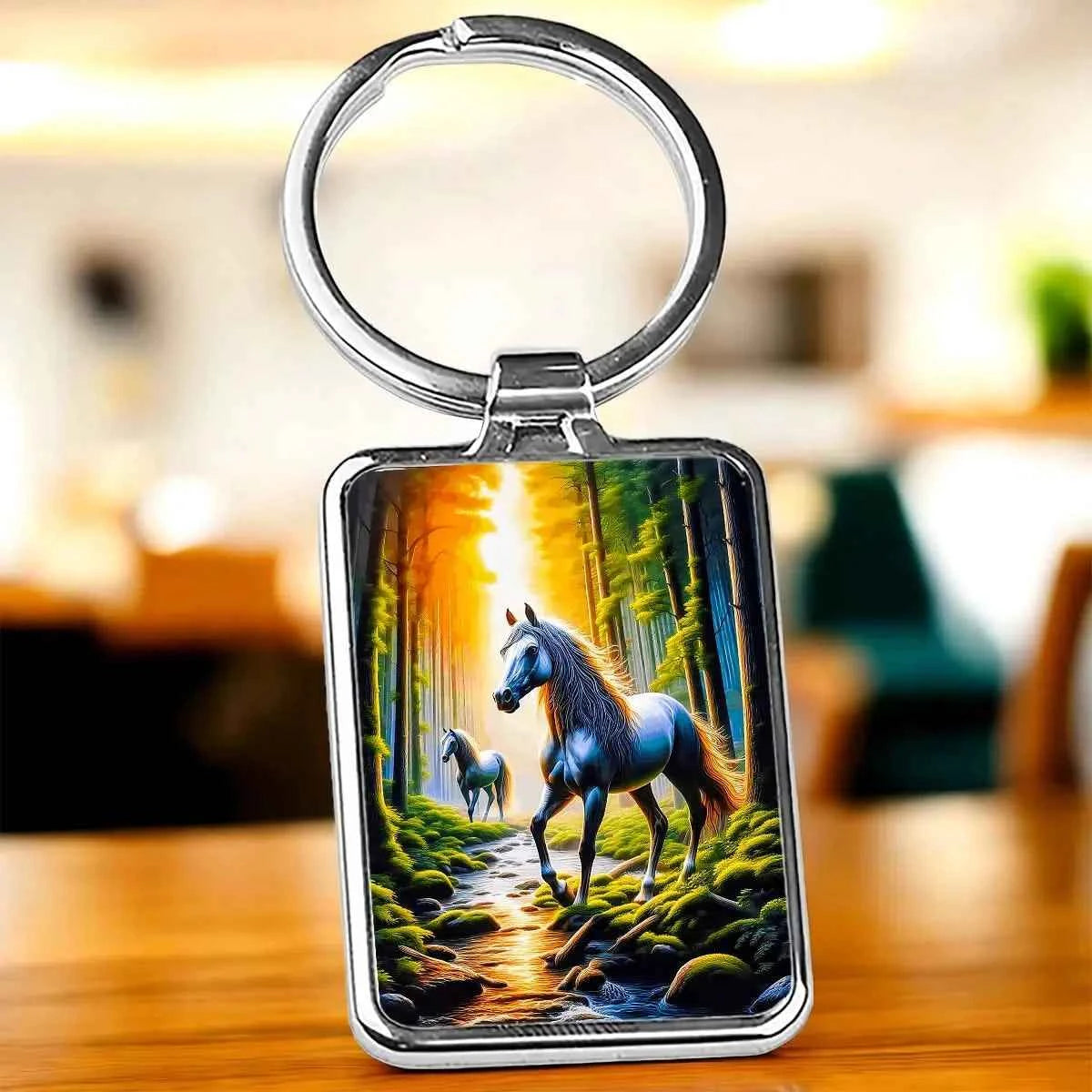 Porte-clés rectangulaire en métal argenté avec un paysage de forêt et deux chevaux.
