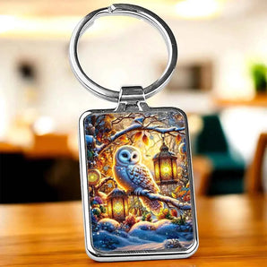 Porte-clés avec un motif d'un hibou blanc sur une branche enneigée illuminée par des lanternes.