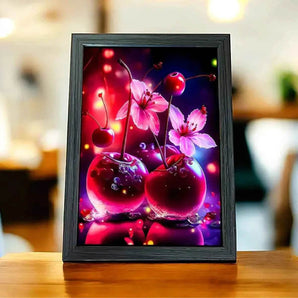 Tableau encadré représentant des cerises et des fleurs roses sur une table en bois.
