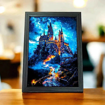 Tableau encadré représentant un château illuminé perché sur une colline sous un ciel étoilé.