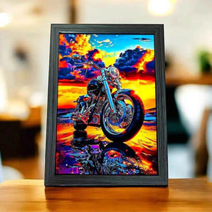 Tableau encadré d'une moto chromée sur fond de coucher de soleil flamboyant.